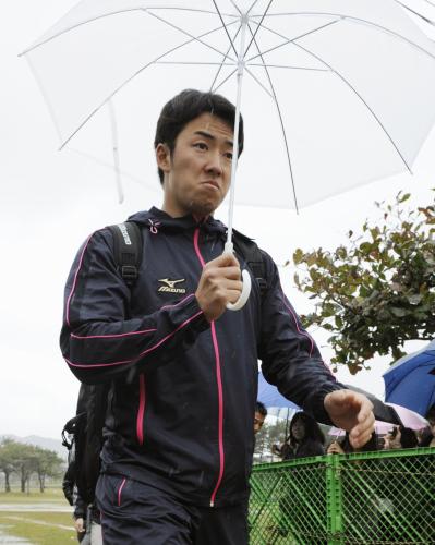 雨の中、傘を差し移動する日本ハム・斎藤