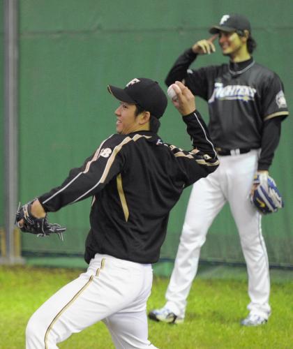 リラックスした表情でキャッチボールする日本ハム・斎藤。右奥はダルビッシュ