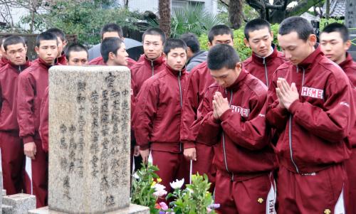 中馬庚さんの墓碑に手を合わせる大館鳳鳴ナイン