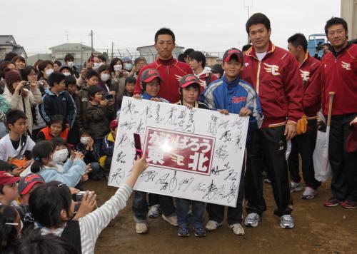 ＜楽天被災地訪問＞避難所となっている東松島市の大曲小の被災者の子供たちと寄せ書きを持つ嶋（左）と田中