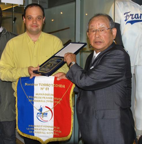 ２０日、パリの国立スポーツ博物館で、フランス野球ソフトボール連盟から贈られたペナントなどを掲げる吉田義男元阪神監督（右）