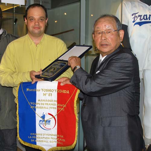 フランス野球ソフトボール連盟から贈られたペナントなどを掲げる吉田氏（右）