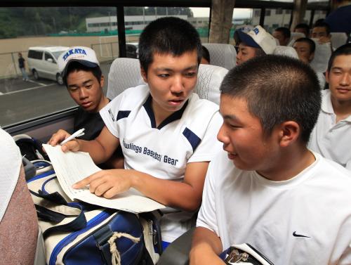 １７日の始業式を前に、練習試合後の移動のバスで夏休みの宿題に取り組む及川（中央）