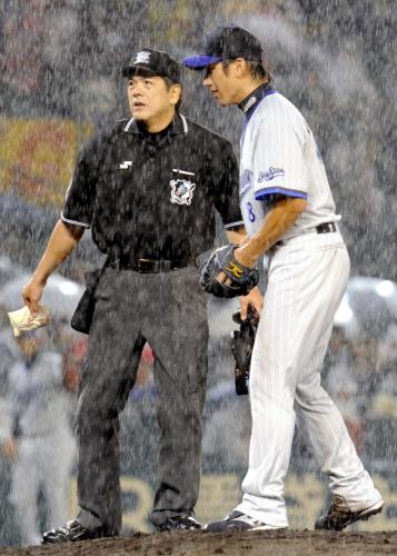 ４回、激しい雨のなかマウンドで球審と話す横浜先発・三浦。この後、試合は中断した