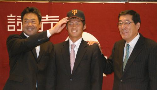 武田康スカウト（左）から帽子をかぶせてもらい、笑顔を見せる一岡竜司。右は山下哲治スカウト部長