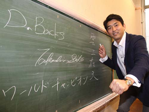 黒板にサインと目標を記し、気合のガッツポーズを見せる斎藤