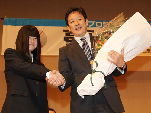 功労賞として日本ハム・栗山監督は、都立清瀬高校野球部マネジャーの上田由衣さんに花束を手渡され笑顔で握手する