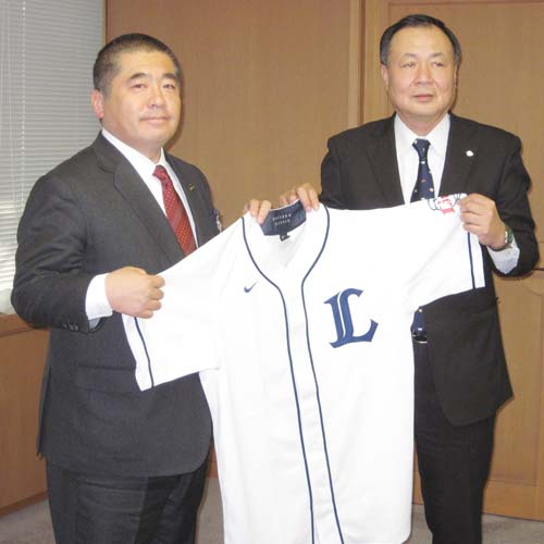 寄贈したユニホームを広げる居郷球団社長（右）と藤本所沢市長