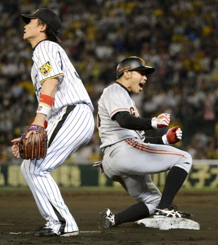 ９回、三塁打を放ちガッツポーズする巨人の代打矢野。左は阪神の三塁手新井良