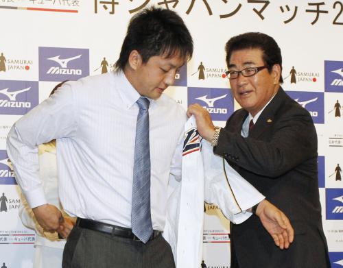 記者会見で、巨人・沢村（左）に日本代表ユニホームを着せる山本監督