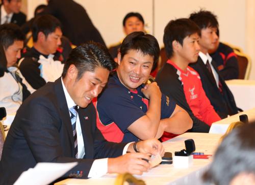 全体ミーティングの席で元同僚の相川（左）と談笑する村田