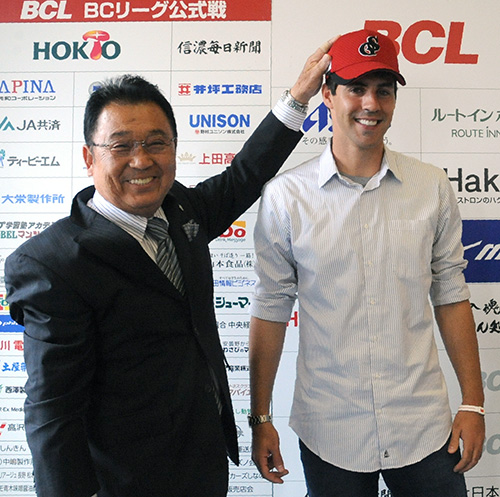 三沢社長（左）から球団の帽子をかぶせてもらい、笑顔を見せるブランドン