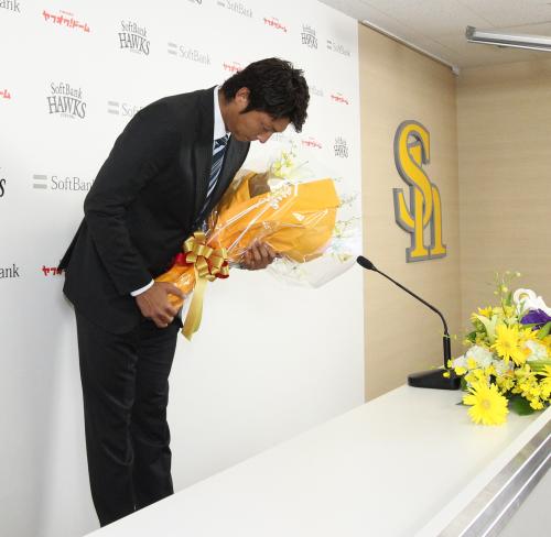 会見終え、花束を手に一礼する斉藤コーチ