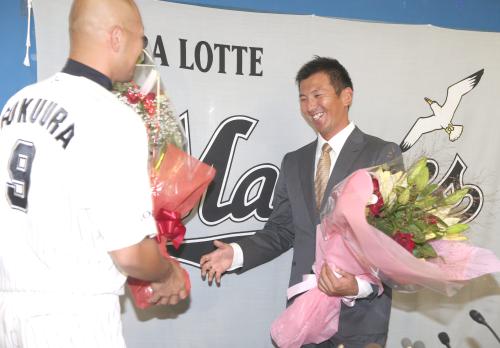引退会見を行った小野（右）は同期入団の福浦から花束を贈られる