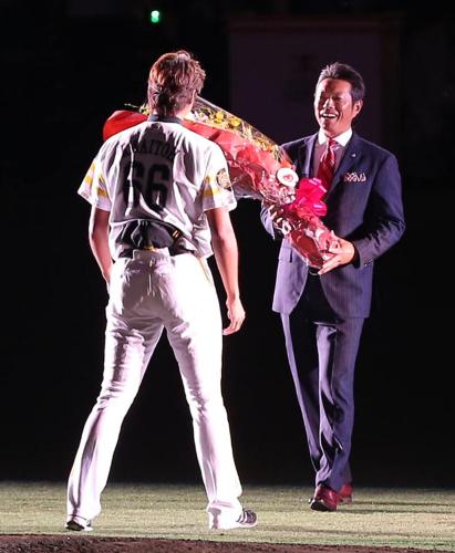 サプライズゲストの小久保氏（右）から花束をもらう斉藤氏