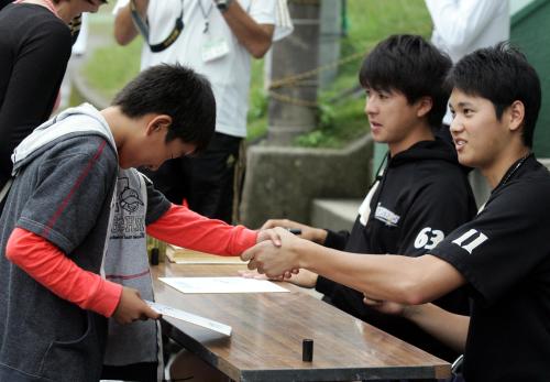 サイン会でちびっ子ファンと握手する大谷（右）