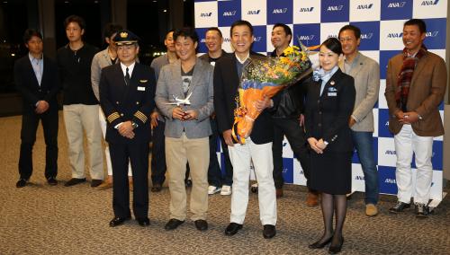 搭乗前に機長、客室乗務員と記念撮影する村田（左）、原監督ら巨人ナイン