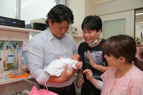 村田（左）は自治医大付属病院を訪問し、新生児を抱く
