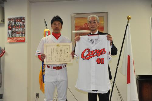チーム代表で使用済みユニホームを広島刑務所の荒関所長（右）に手渡し、感謝状を贈られた久本