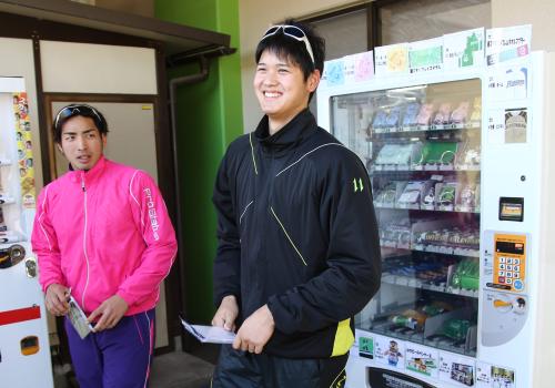 期間限定で鎌ケ谷スタジアムに登場したファイターズ「グッズが買える自動販売機」でメモ帳を購入した大谷はこの日一番の笑顔。左は屋宜