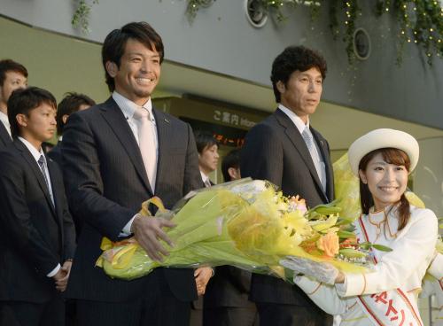 宮崎空港に到着し、歓迎の花束を受け取るソフトバンク・松田。右は秋山監督