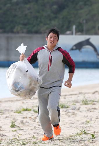 ビーチクリーンを行い、ゴミを手に砂浜を走る松井裕