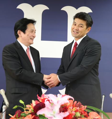 就任会見で鈴木球団本部長（左）と笑顔で握手を交わす緒方新監督