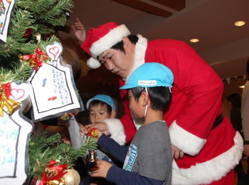 子どもたちのクリスマスツリーへの飾りつけを手伝う中村