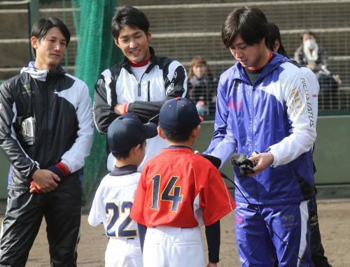 じゃんけん大会に勝利した子供に野球道具のプレゼントをする広島・野村（右）。左は巨人・小林
