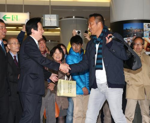 広島空港に到着した黒田（右）は鈴木球団本部長の出迎えを受け笑顔を見せる