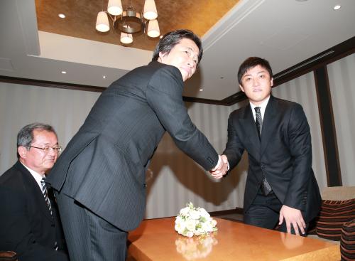 阪神・高野球団本部長（中央）と握手する高橋聡。左は阪神の池之上球団本部課長