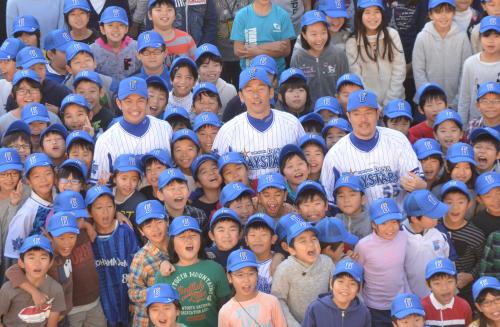 球団５周年記念ロゴが入った帽子をかぶった小学生に囲まれ笑顔の（左から）山崎康、三浦、後藤