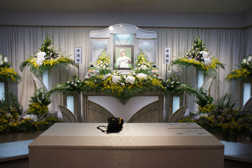 安達氏の祭壇。棺の上には友人が置いた袋に入ったグローブが