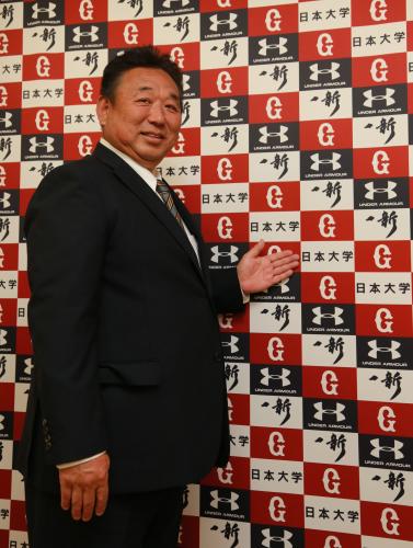 日大と巨人のマークが印刷されたパネルを示し笑顔の日大スポーツ科学部・小山裕三教授