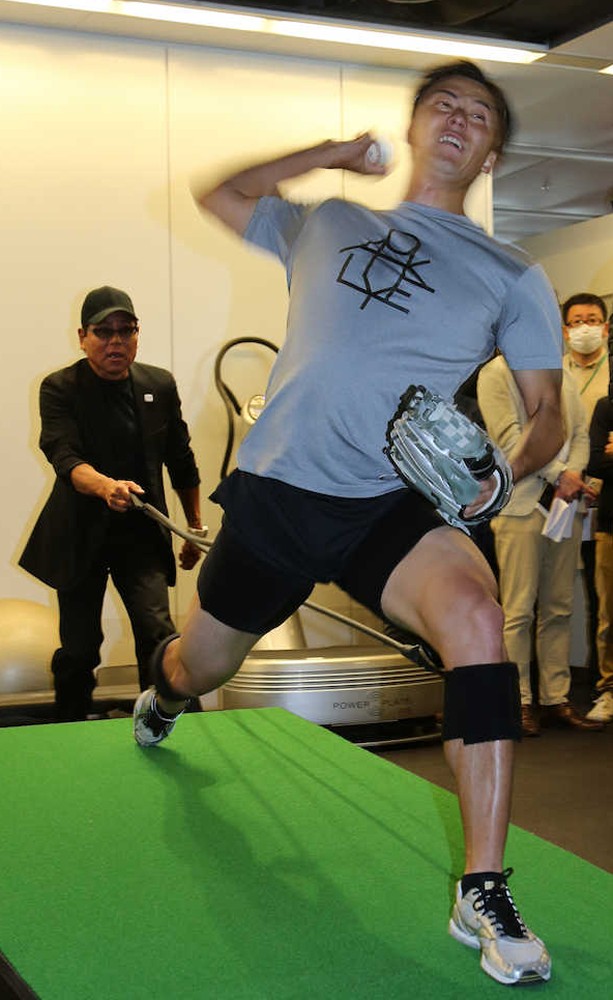 スプリントコードトレーニングでケビン山崎氏（左）に引っ張られながら投球練習をする斎藤
