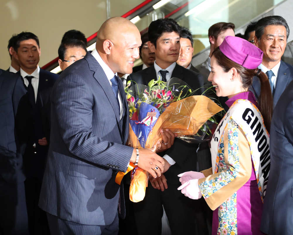 那覇空港に到着し花束を受け取るラミレス監督（左）