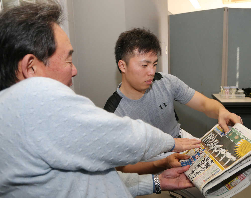 東尾氏（左）がフォームを分析したスポニチ本紙を見る田中