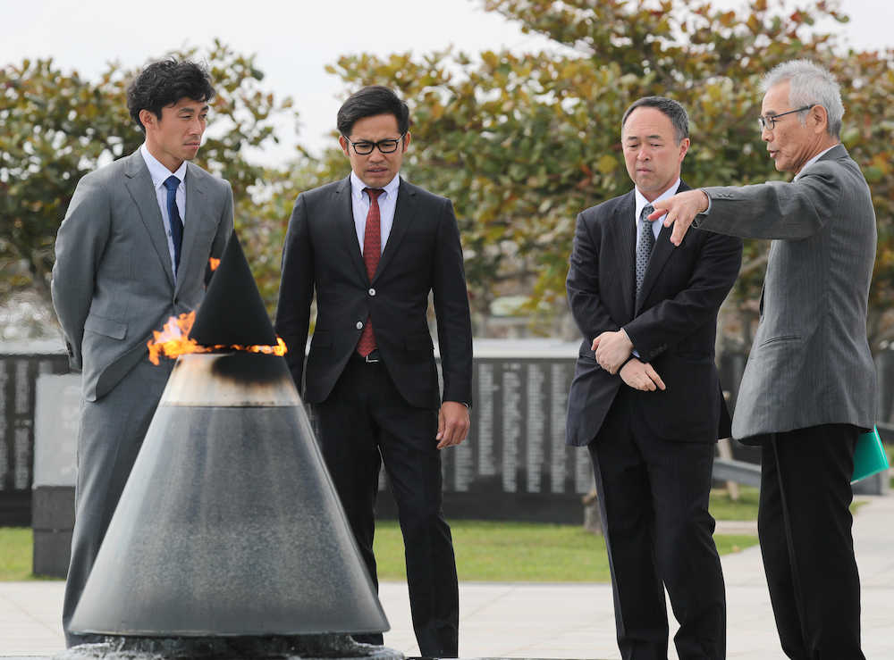 平和の火の前で説明を受ける（左から）吉川光、森福、堤辰佳ＧＭ