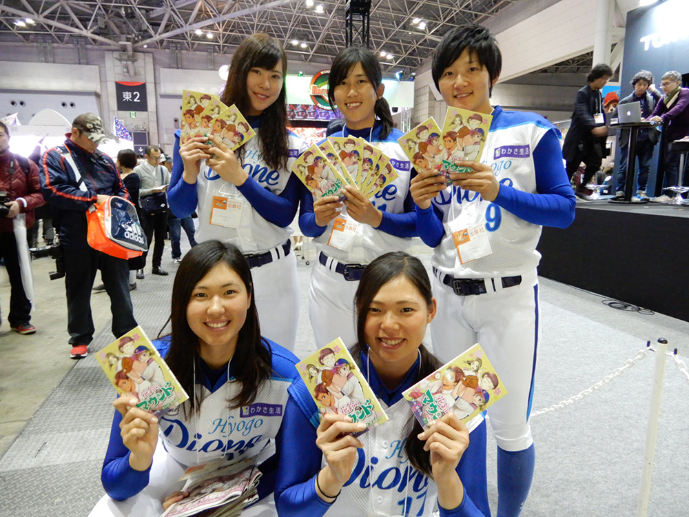 女子野球マンガ「花鈴のマウンド」特別版を配布する兵庫ディオーネの選手たち（前列左から古谷、泉、後列左からみなみ、坂東、三浦）