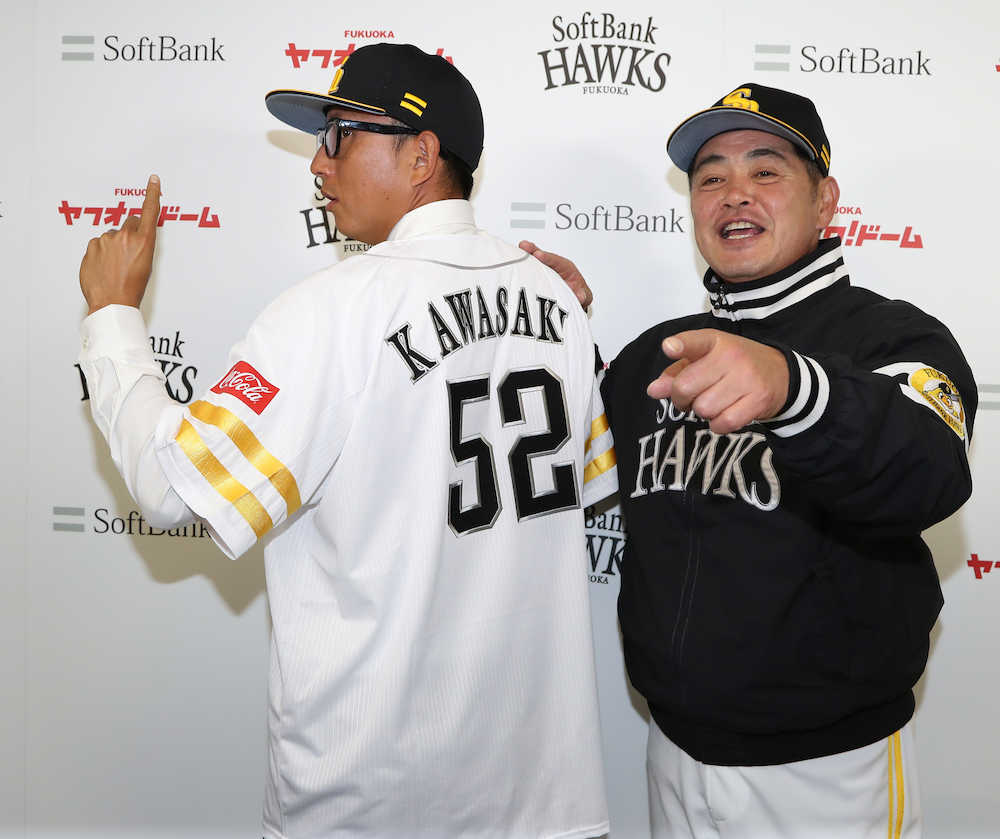 背番号「５２」のユニホームに袖を通しポーズする川崎。右は工藤監督