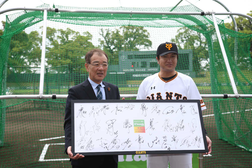 ＜巨・ヤ＞試合前、打撃ゲージの贈呈式が行われ、田嶋熊本県副知事（左）にサインの寄書きを贈る高橋監督