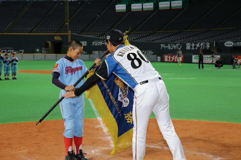 「ＦＩＧＨＴＥＲＳ　ＢＡＳＥＢＡＬＬ　ＣＨＡＭＰＩＯＮＳＨＩＰ　Ｕ―１２」で優勝旗を東１６丁目フリッパーズの選手に手渡す日本ハム・栗山監督