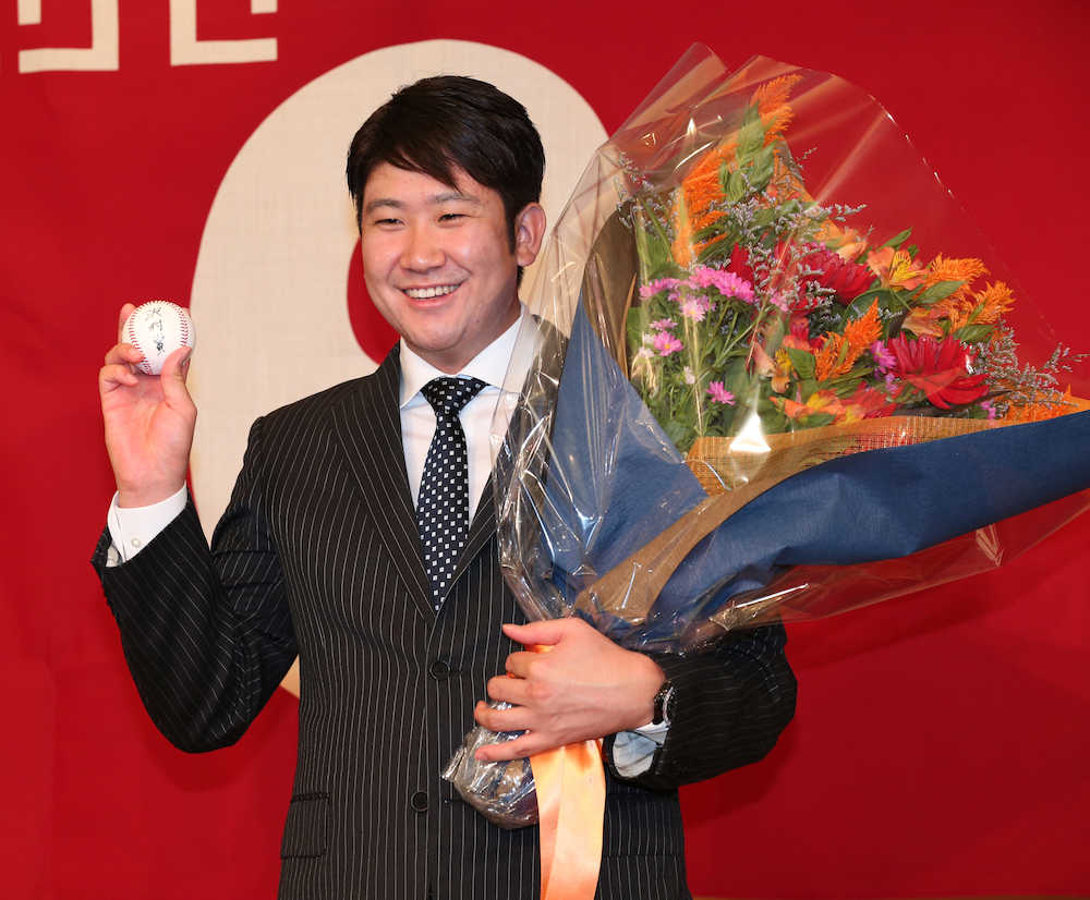 「沢村賞」と書かれたボールと花束を手に笑顔の菅野