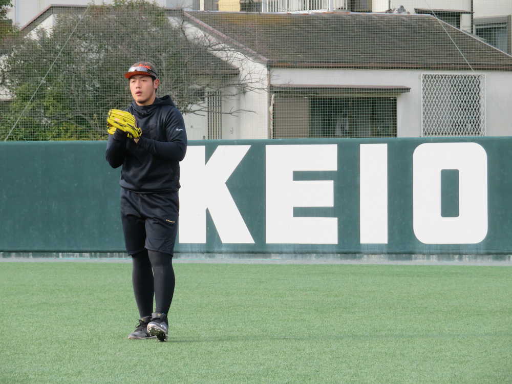 慶大グラウンドでキャッチボールする巨人・岡本。後ろには「ＫＥＩＯ」の文字
