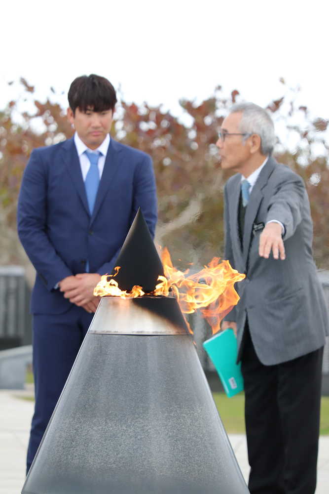 平和祈念公園を参拝し、平和の火の説明を受ける巨人・菅野（左）