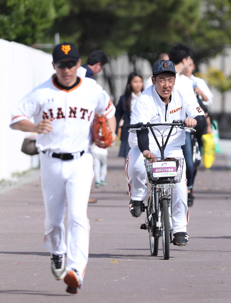 ノックを終え伊藤トレーニングコーチ（左）と自転車で競争する岡本