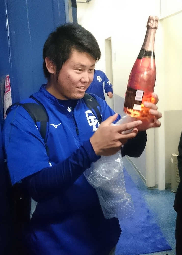 森監督から光るボトルに入ったシャンパンをプレゼントされ、まじまじと見つめる鈴木博