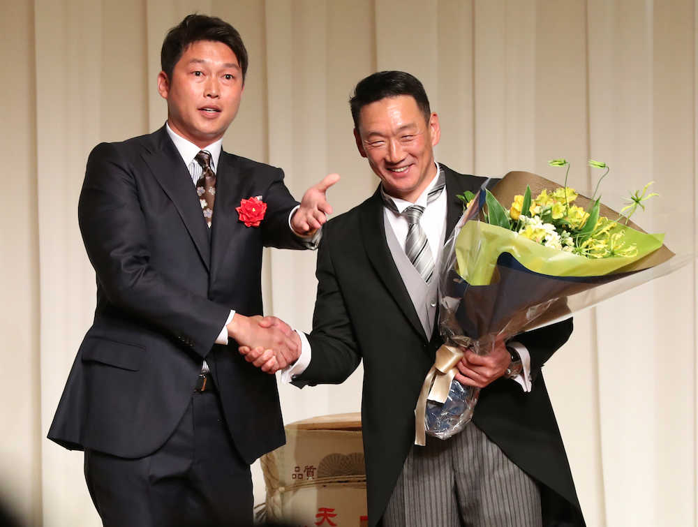 新井貴浩氏（左）から花束を受け取り、笑顔の金本知憲氏（撮影・北條　貴史）　　　