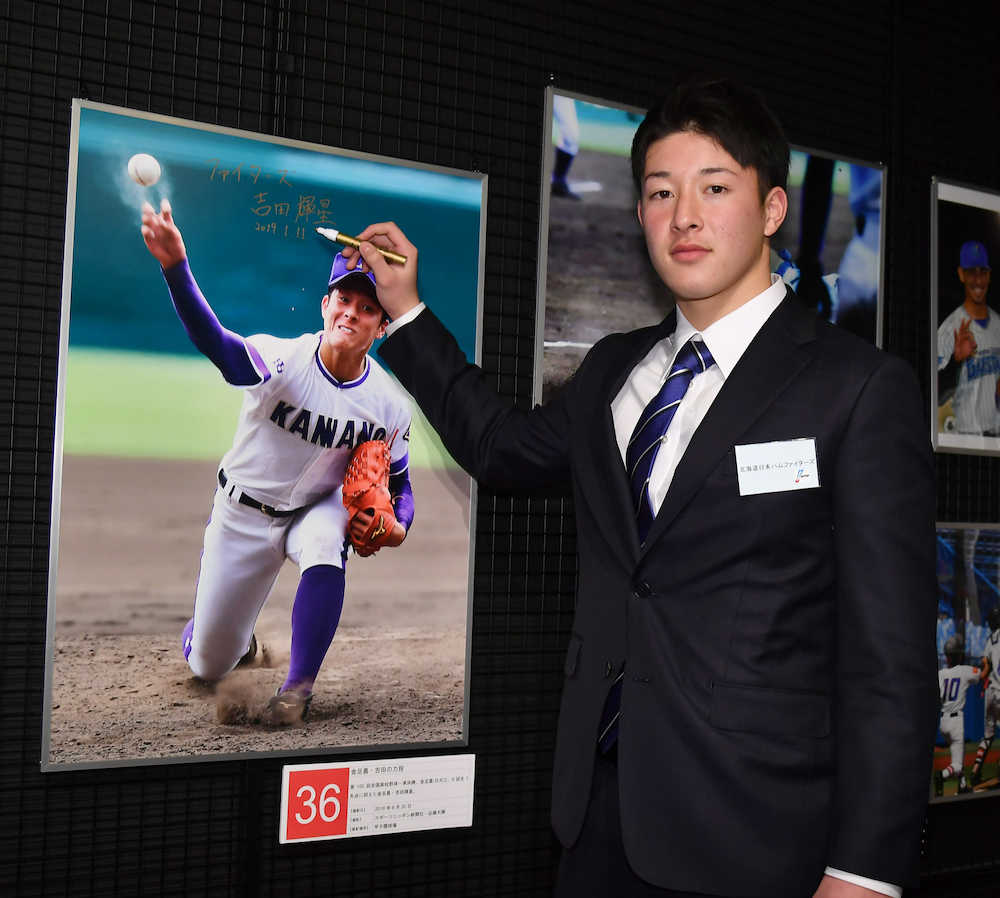 野球殿堂博物館を見学し、写真展で飾られた自身の写真にサインする日本ハムの吉田輝星（代表撮影）