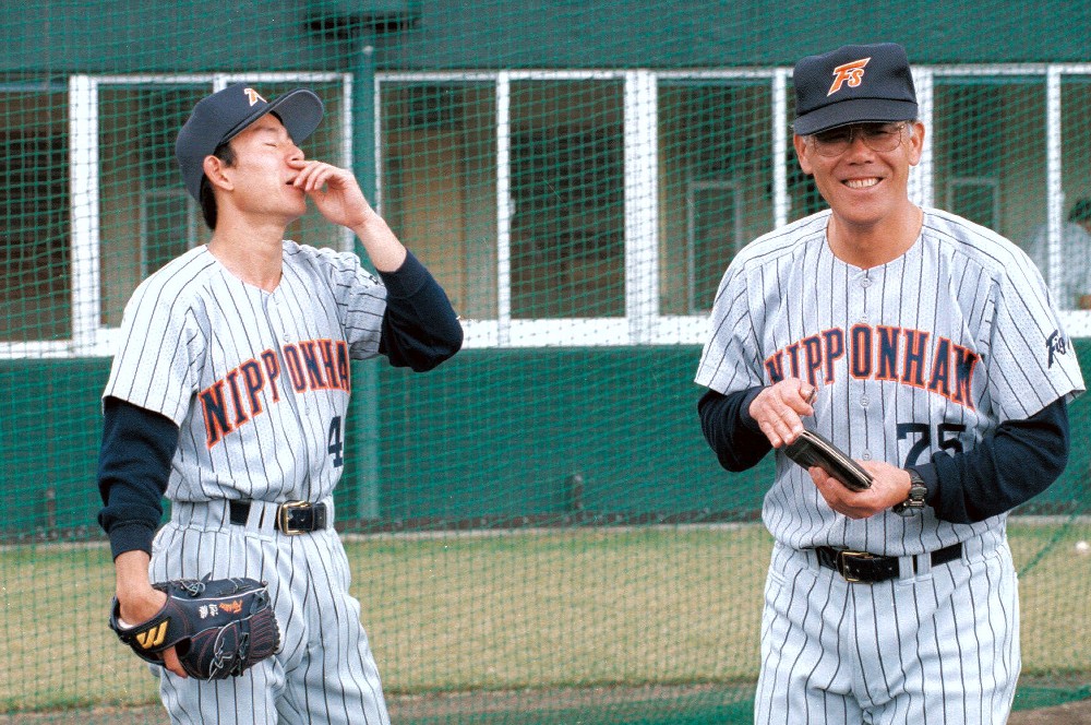 ００年２月、練習中に突然鼻血を出した遠藤（左）を見て笑う浅野投手コーチ